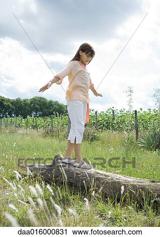 Girl standing on log in field View Large Photo Image Stock Image - Girl standing on log in field. Fotosearch