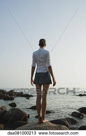 Girl standing on rock looking at ocean View Large Photo Image Stock Image - Girl standing on rock looking at ocean. Fotosearch