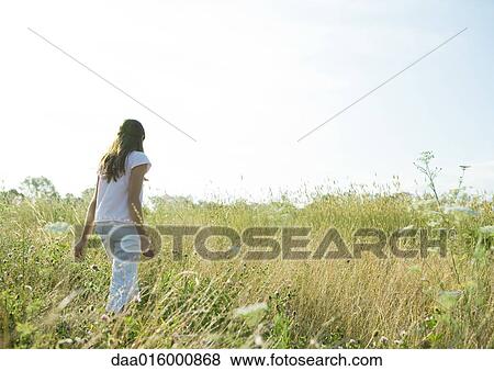 Girl walking through tall grass in field View Large Photo Image Stock Photo - Girl walking through tall grass in field. Fotosearch