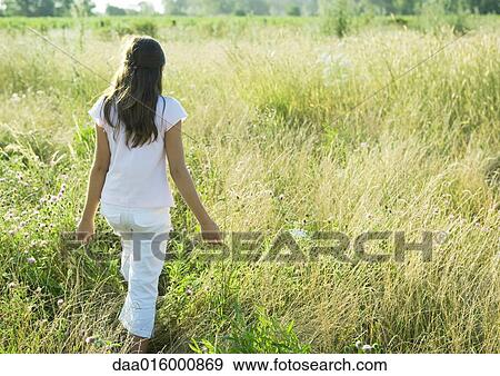 Girl walking through tall grass in field View Large Photo Image Stock Photo - Girl walking through tall grass in field. Fotosearch