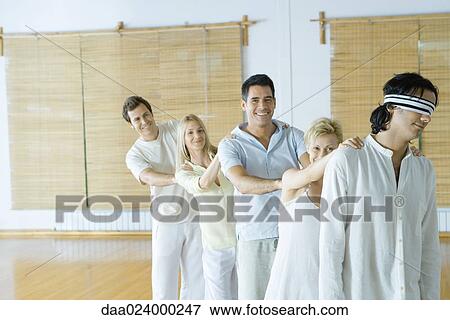 Group of adults standing single file holding onto each others' shoulders, leader blindfolded View Large Photo Image Stock Photo - Group of adults standing single file holding onto each others' shoulders, leader blindfolded. Fotosearch