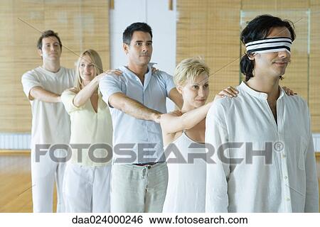 Group of adults standing single file holding onto each others' shoulders, leader blindfolded View Large Photo Image Stock Photograph - Group of adults standing single file holding onto each others' shoulders, leader blindfolded. Fotosearch