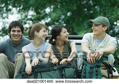 Stock Image - Group of hikers sitting in back of pick-up truck. Fotosearch