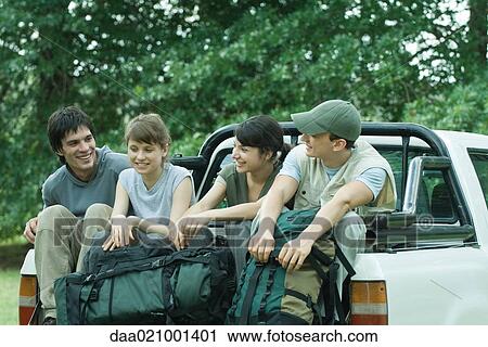 Stock Image - Group of hikers sitting in back of pick-up truck. Fotosearch