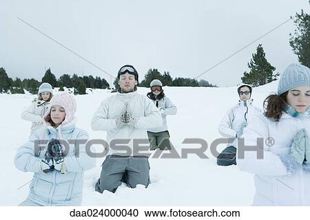 Group of young friends kneeling in snow with hands clasped and eyes shut View Large Photo Image Stock Image - Group of young friends kneeling in snow with hands clasped and eyes shut. Fotosearch