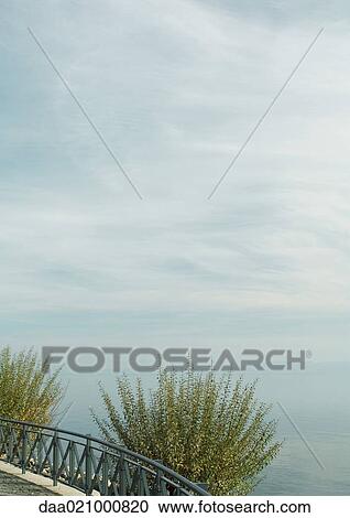 Guardrail and bushes overlooking body of water View Large Photo Image Stock Image - Guardrail and bushes overlooking body of water. Fotosearch