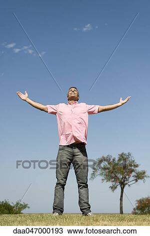 Happy man standing outdoors with arms raised, full length View Large Photo Image Stock Image - Happy man standing outdoors with arms raised, full length. Fotosearch