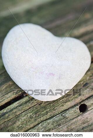 Stock Image - Heart-shaped stone on wood. Fotosearch