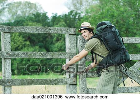 Hiker with backpack closing wooden fence View Large Photo Image Stock Photograph - Hiker with backpack closing wooden fence. Fotosearch