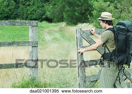 Hiker with backpack opening wooden fence View Large Photo Image Stock Photography - Hiker with backpack opening wooden fence. Fotosearch