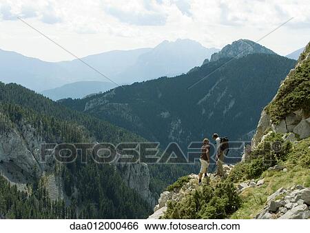 Stock Photograph - Hikers looking at mountainous landscape. Fotosearch