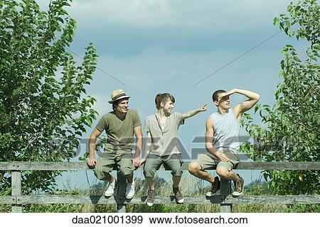 Hikers sitting on wooden fence, looking toward distance View Large Photo Image Stock Photo - Hikers sitting on wooden fence, looking toward distance. Fotosearch