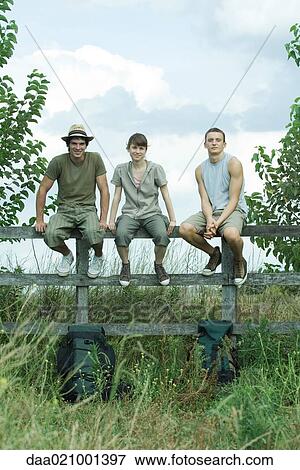 Hikers sitting on wooden fence View Large Photo Image Stock Photo - Hikers sitting on wooden fence. Fotosearch