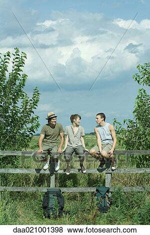 Hikers sitting on wooden fence View Large Photo Image Stock Photo - Hikers sitting on wooden fence. Fotosearch