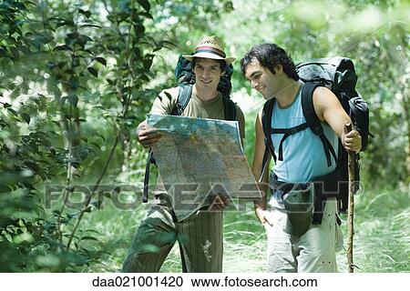 Stock Image - Hikers standing, looking at map. Fotosearch