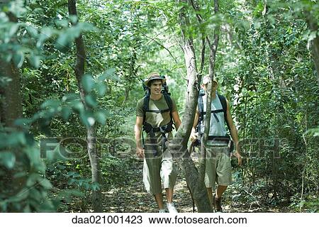 Stock Image - Hikers walking through woods. Fotosearch