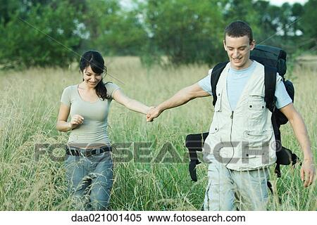 Stock Photography - Hiking couple walking through field. Fotosearch