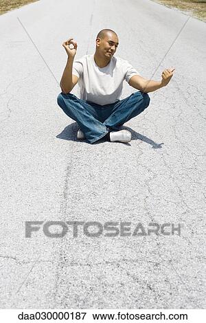 Hitchhiker sitting in the middle of the road in lotus position, holding one thumb out View Large Photo Image Stock Photo - Hitchhiker sitting in the middle of the road in lotus position, holding one thumb out. Fotosearch