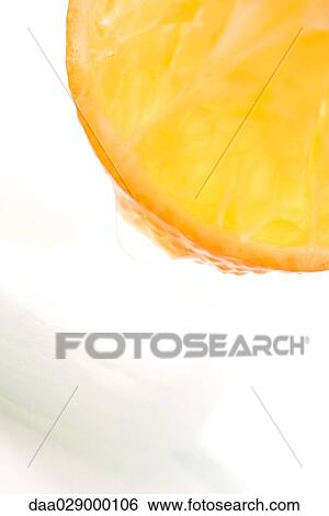 Stock Photograph - Juicy fruit dripping on to cotton cosmetic pad, extreme close-up. Fotosearch