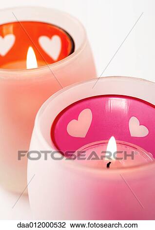 Stock Image - Lit candles in candleholder with heart pattern. Fotosearch