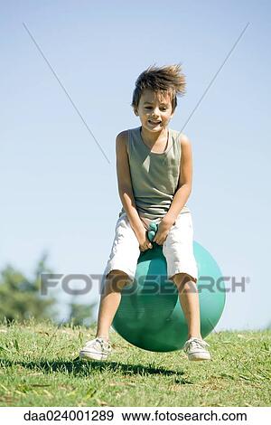 Little boy outdoors, jumping on ball, full length View Large Photo Image Stock Photo - Little boy outdoors, jumping on ball, full length. Fotosearch