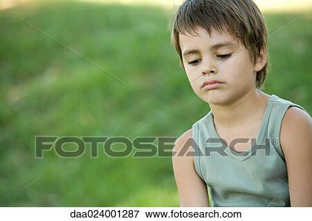 Stock Photo - Little boy outdoors, looking down. Fotosearch