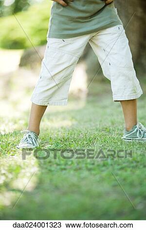 Stock Image - Little boy outdoors, standing on grass, waist down. Fotosearch