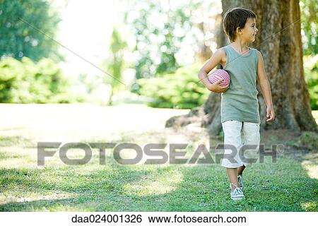 Little boy outdoors, walking with ball View Large Photo Image Stock Photograph - Little boy outdoors, walking with ball. Fotosearch