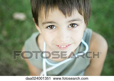 Stock Image - Little boy outdoors, wearing toy stethoscope around neck, high angle view. Fotosearch