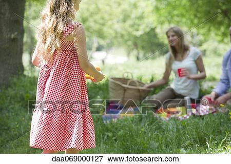 Stock Photo - Little girl having picnic with family. Fotosearch