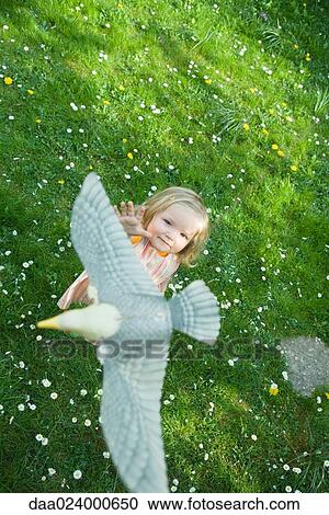 Little girl reaching for fake bird View Large Photo Image Stock Image - Little girl reaching for fake bird. Fotosearch