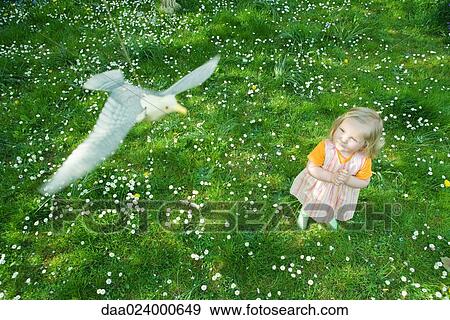 Stock Photo - Little girl watching fake bird hanging from string. Fotosearch