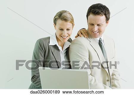 Male and female business associates using laptop computer together, both smiling View Large Photo Image Stock Photo - Male and female business associates using laptop computer together, both smiling. Fotosearch