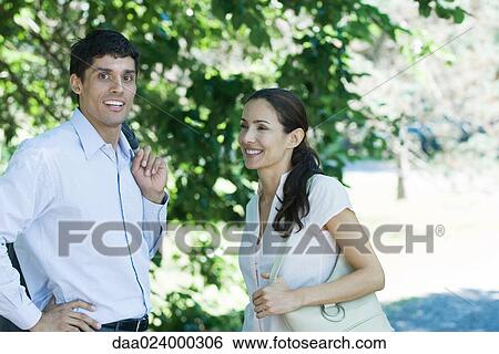 Man and woman standing in park, smiling View Large Photo Image Stock Photograph - Man and woman standing in park, smiling. Fotosearch