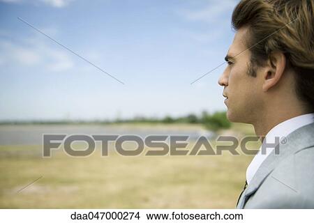 Man at lake shore contemplatively looking at view View Large Photo Image Picture - Man at lake shore contemplatively looking at view. Fotosearch