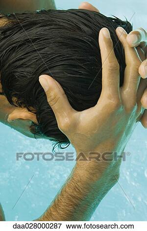 Stock Photo - Man bending over swimming pool, wetting head with water, cropped rear view. Fotosearch