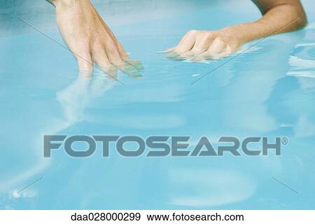 Stock Photo - Man dipping hands in water, close-up, cropped. Fotosearch