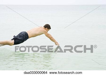 Picture - Man diving into the ocean, side view. Fotosearch