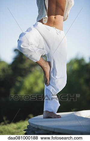 Stock Photo - Man doing tree pose, low section. Fotosearch