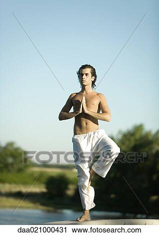 Stock Image - Man doing yoga pose outdoors. Fotosearch