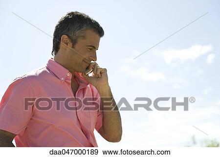 Man having conversation on cell phone, outdoors, smiling View Large Photo Image Stock Photo - Man having conversation on cell phone, outdoors, smiling. Fotosearch
