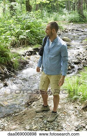 Man hiking along stream in woods View Large Photo Image Stock Photo - Man hiking along stream in woods. Fotosearch