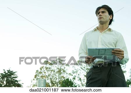 Stock Photo - Man holding blueprints, low angle view. Fotosearch
