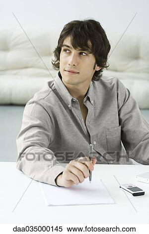 Man holding pen above paper, looking away View Large Photo Image Stock Photography - Man holding pen above paper, looking away. Fotosearch