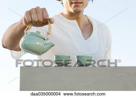 Man holding teapot, cropped, mid section View Large Photo Image Picture - Man holding teapot, cropped, mid section. Fotosearch