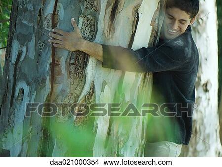 Man hugging tree, smiling, eyes closed View Large Photo Image Picture - Man hugging tree, smiling, eyes closed. Fotosearch
