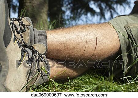 Man in hiking boots relaxing on grass with legs crossed, low section View Large Photo Image Stock Photo - Man in hiking boots relaxing on grass with legs crossed, low section. Fotosearch