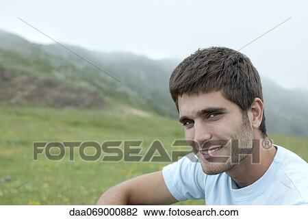 Stock Image - Man in nature, mountains in background, portrait. Fotosearch