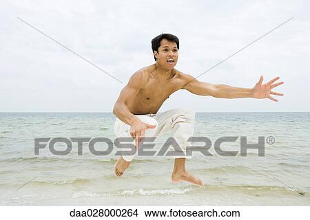 Man jumping in the air and shouting, ocean in background View Large Photo Image Picture - Man jumping in the air and shouting, ocean in background. Fotosearch