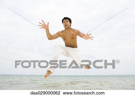 Man jumping in the air at the beach View Large Photo Image Stock Image - Man jumping in the air at the beach. Fotosearch